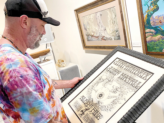 Brian Chambers, gallery owner admiring a Jimi Hendrix concert poster