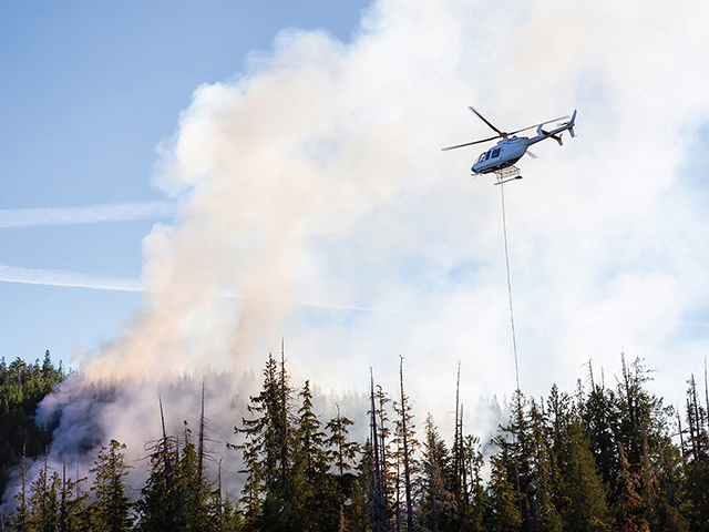 fighting forest fire with helicopter dumping water